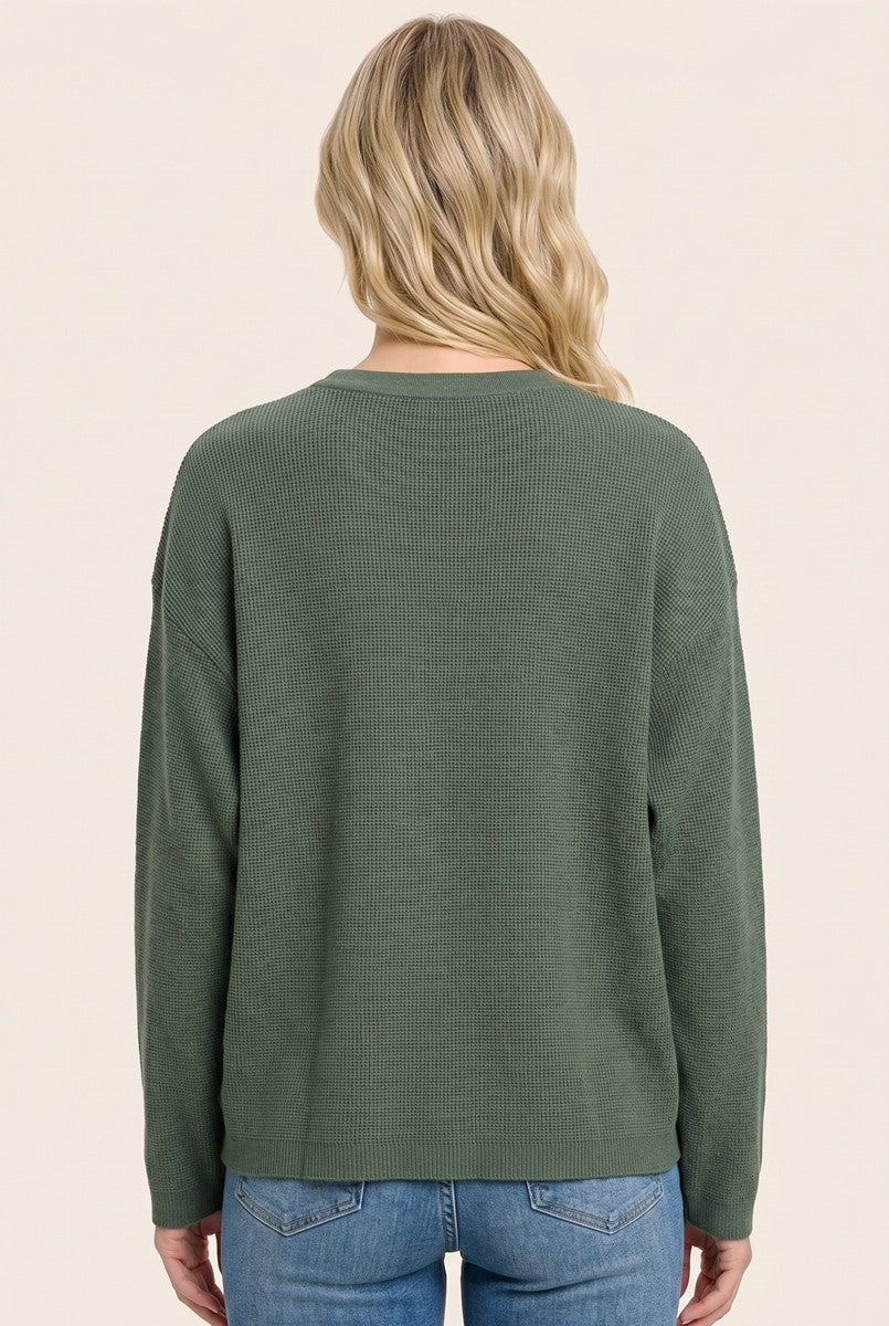 woman wearing a green ribbed long sleeve sweater, viewed from the back, paired with light blue jeans