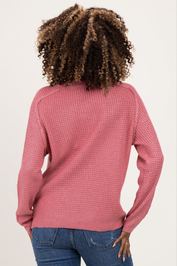 woman wearing a pink knit maternity sweater, viewed from the back, with long sleeves and a relaxed fit