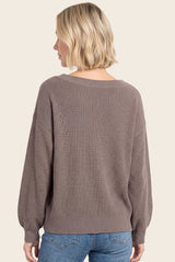 woman wearing a taupe oversized knit sweater with a textured fabric and balloon sleeves, viewed from the back