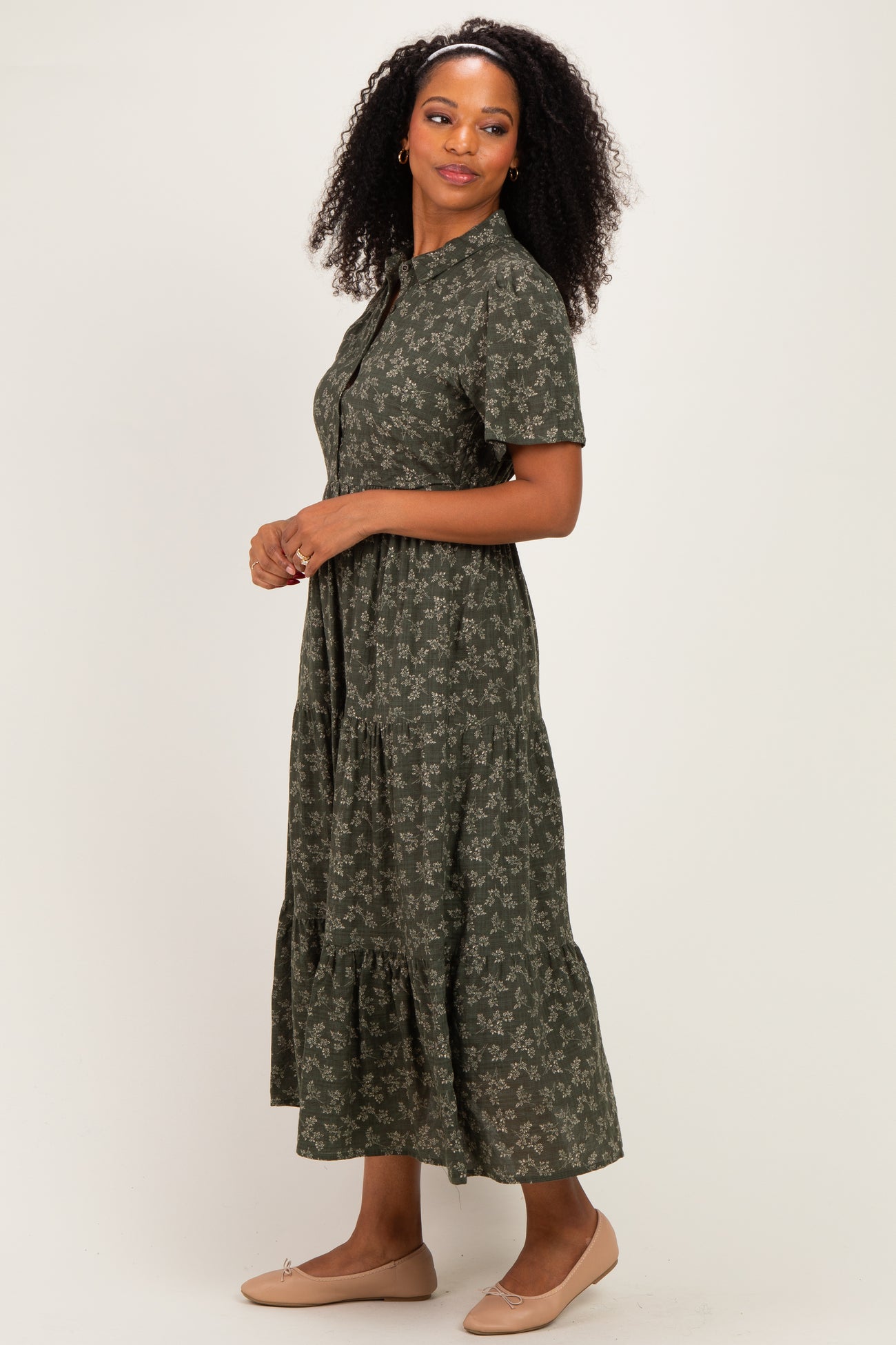 woman wearing a dark green floral print midi dress with short sleeves and a tiered skirt