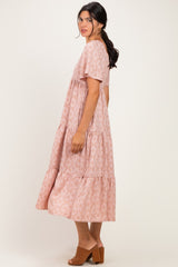 woman wearing a pink floral maxi dress with short sleeves and a tiered hem, standing sideways