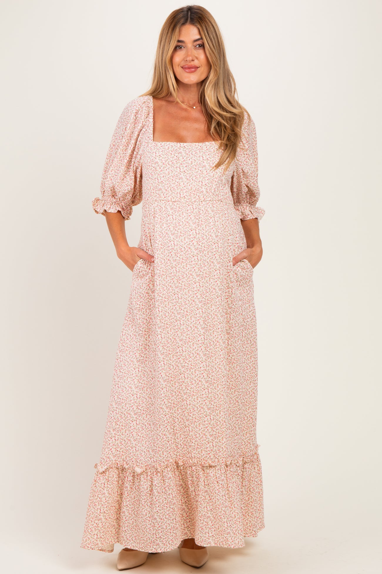 woman wearing a pink floral maternity maxi dress with puff sleeves and side pockets