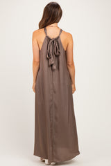 woman wearing a brown maternity maxi dress with a halter neck and bow detail at the back