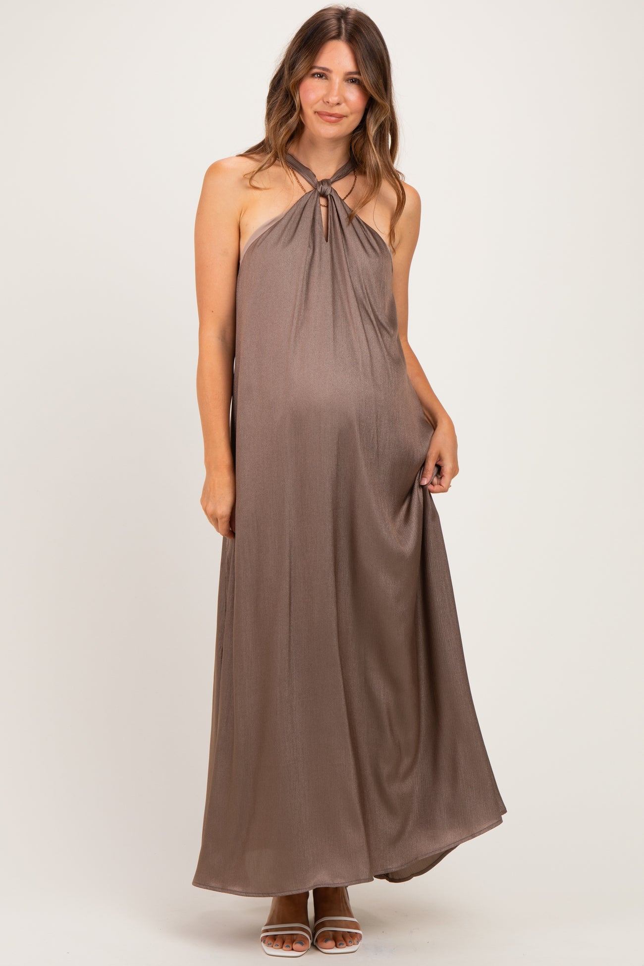 woman wearing a brown halter neck maxi maternity dress with a keyhole detail and a visible baby bump