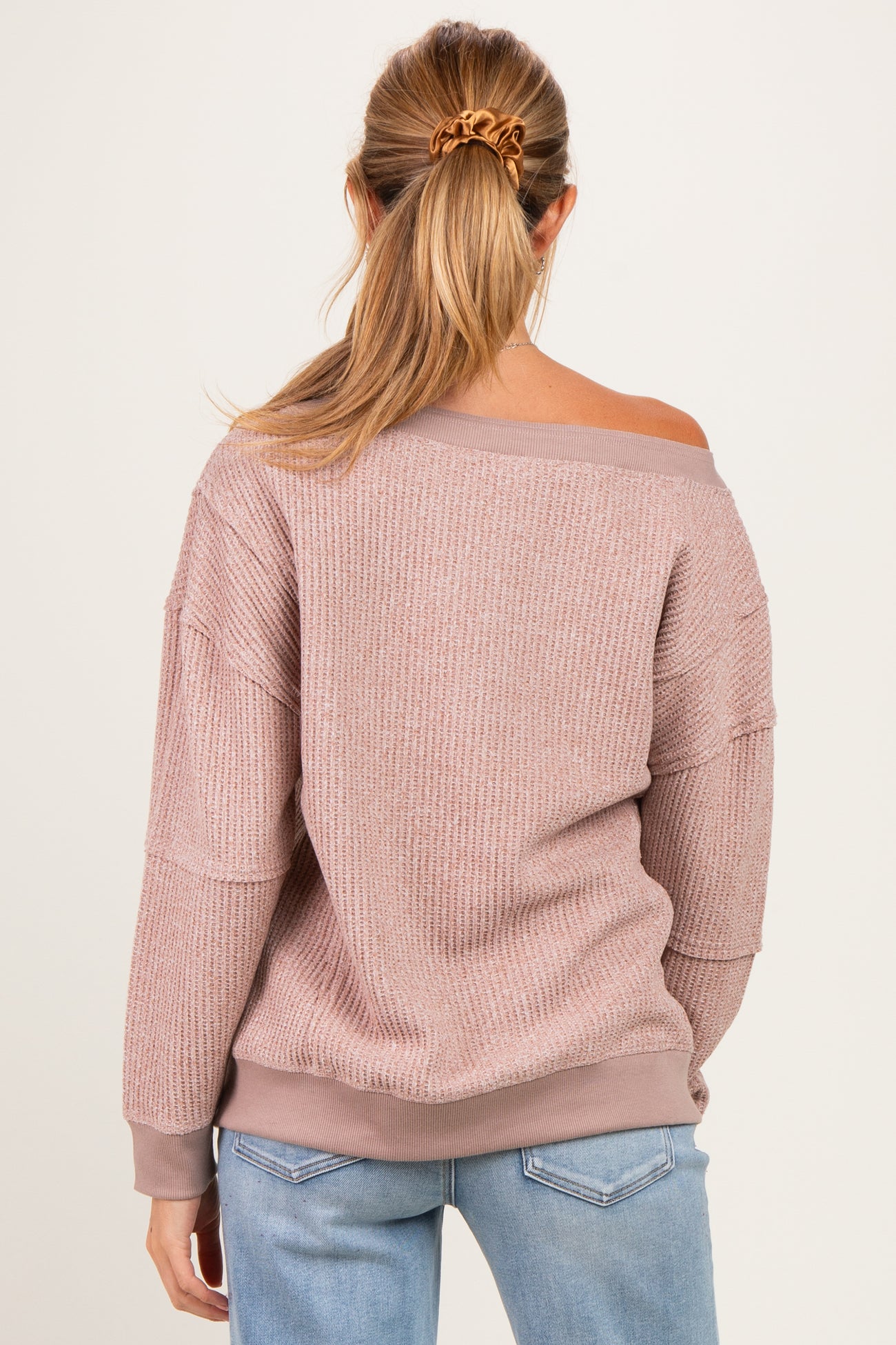woman wearing a light pink off-shoulder maternity sweater with ribbed texture and long sleeves