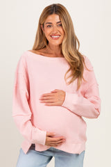 woman wearing a light pink knit maternity sweater and holding her baby bump