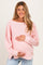 woman wearing a light pink knit maternity sweater and holding her baby bump