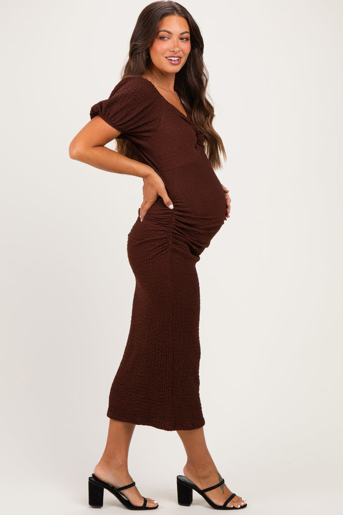 woman wearing a brown maternity dress with short sleeves and ruching, showing her baby bump