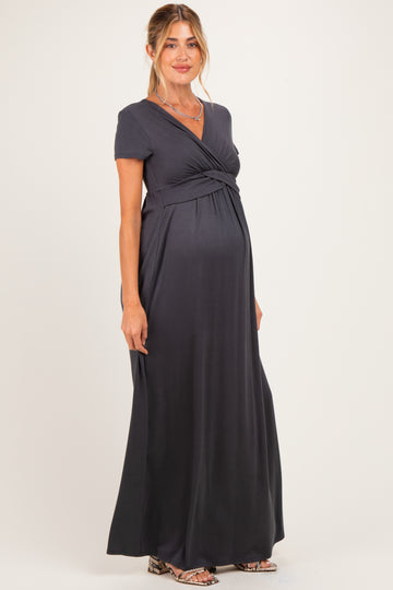 woman wearing a dark gray short sleeve maternity dress with a wrapped bodice and visible baby bump