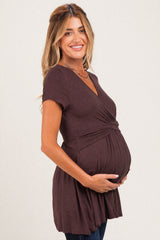 woman wearing a dark brown maternity top with a wrap-style front and a visible baby bump