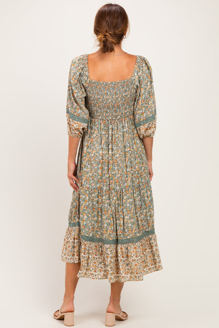 woman wearing a floral midi dress with a square neckline and puff sleeves, showing a gathered bodice and tiered skirt