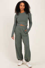 woman wearing a long sleeve olive green cropped top and matching wide-leg pants, paired with white sneakers