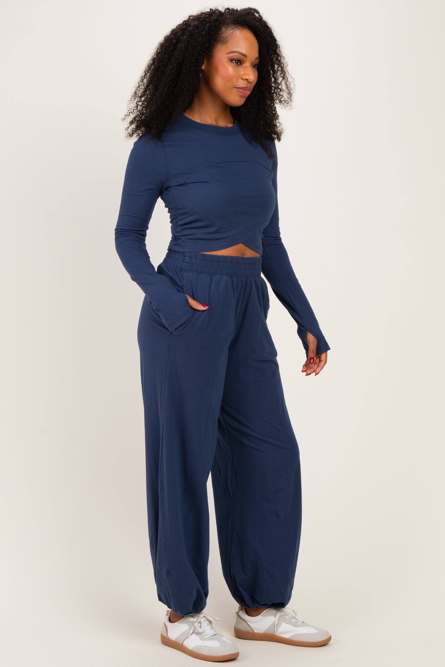 woman wearing a navy long sleeve cropped top and matching wide-leg pants, standing with hands in pockets
