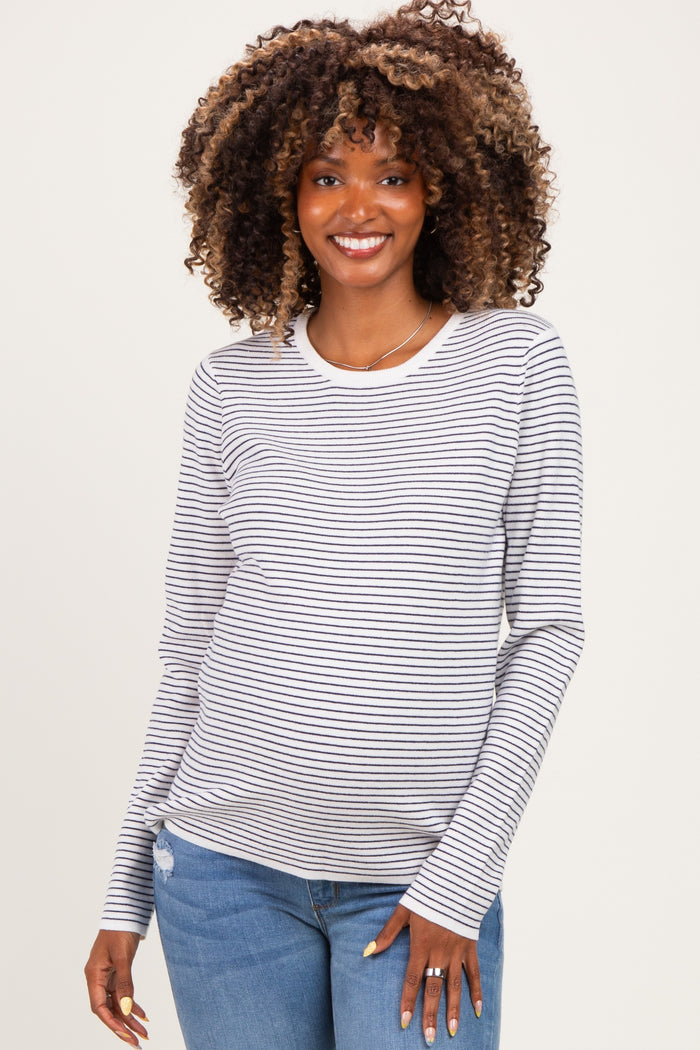 woman wearing a striped maternity top with long sleeves and a visible baby bump, paired with light blue jeans