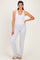 woman wearing a white sleeveless bodysuit and light gray lounge pants, posing with one hand on her hip