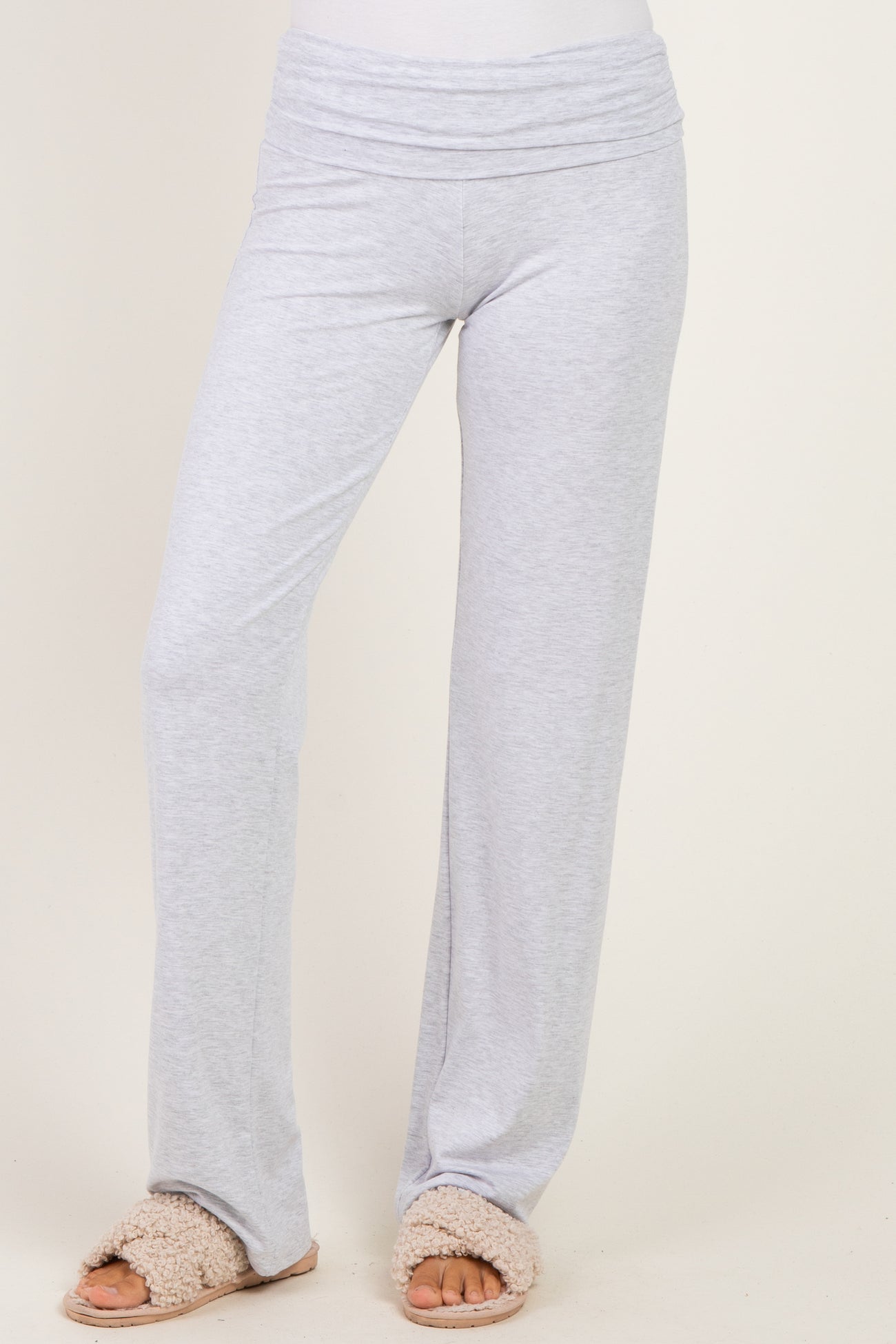 woman wearing light gray wide-leg lounge pants with a fold-over waistband and slip-on fluffy slippers