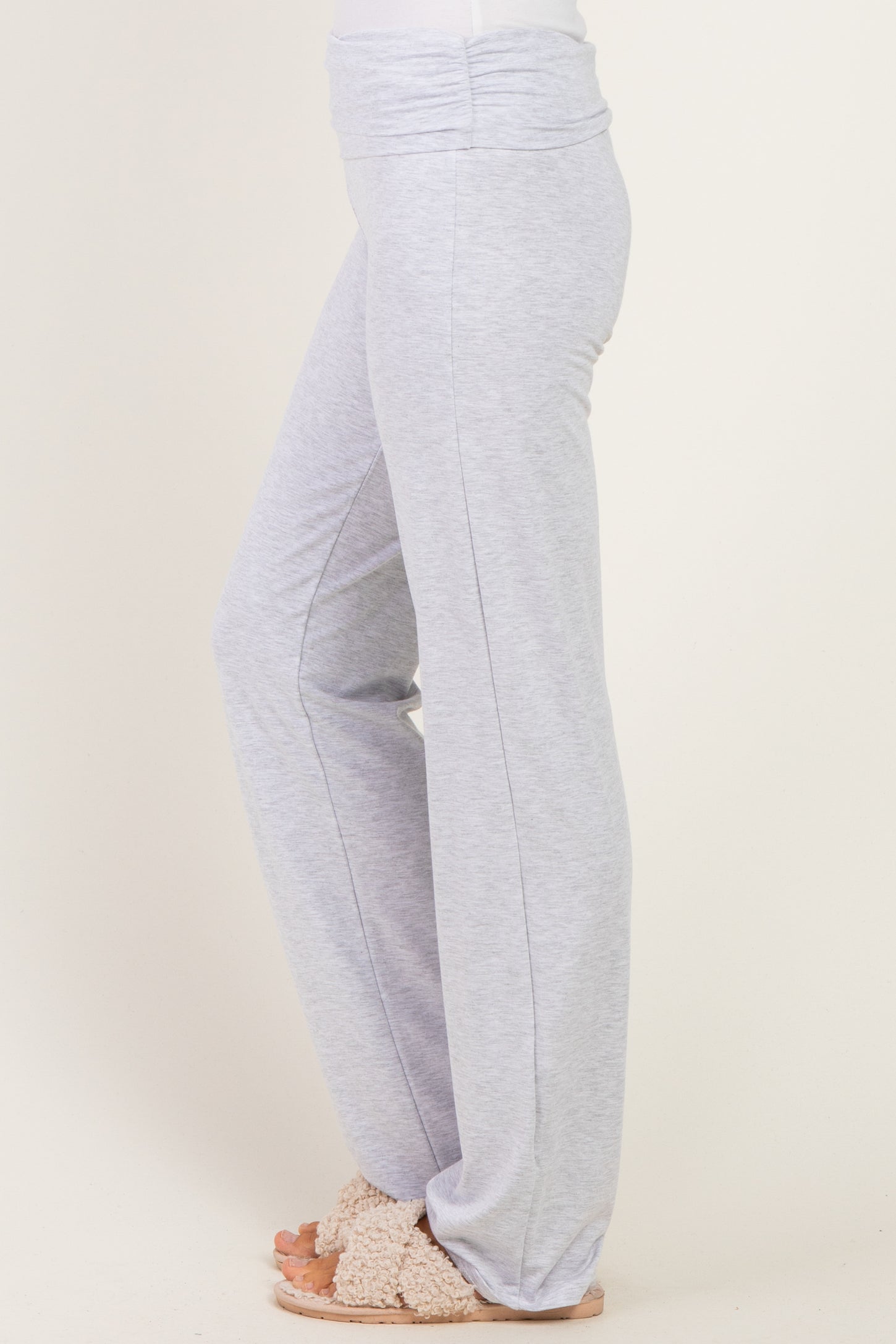 woman wearing light grey lounge pants with a wide waistband and loose fit, paired with cozy slippers