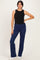 woman wearing a black sleeveless top and navy blue wide-leg pants, posing with one hand on her hip