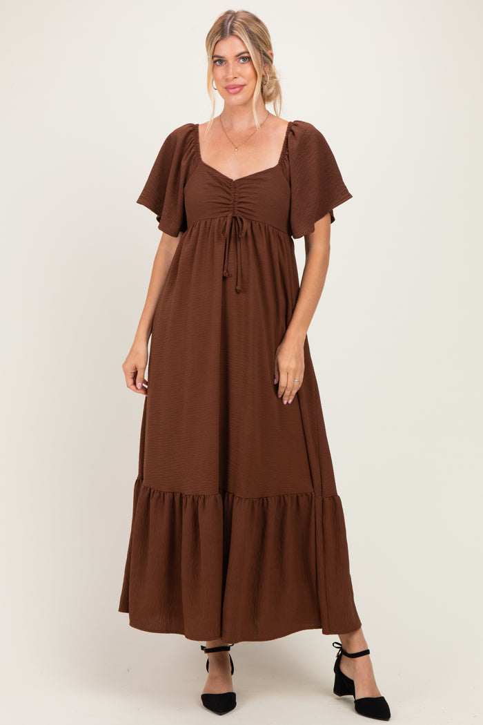 woman wearing a brown maxi dress with short puff sleeves and drawstring detail at the neckline