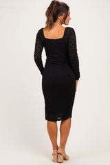 woman wearing a black lace long sleeve maternity dress, showing a form-fitting silhouette from the back