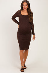 woman wearing a brown lace maternity dress with long sleeves and a fitted silhouette, showcasing her baby bump