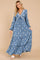 woman wearing a blue floral maxi dress with long sleeves and a tie detail at the neckline