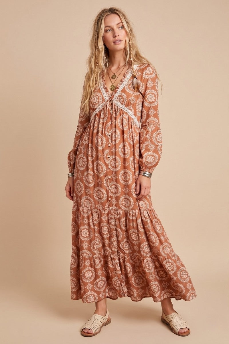 woman wearing a brown patterned maxi dress with long sleeves and a tiered skirt, styled with accessories