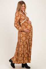 woman wearing a brown floral long sleeve maternity dress and holding her baby bump