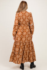 woman wearing a brown floral print maternity maxi dress with long sleeves and tiered hem. baby bump not visible