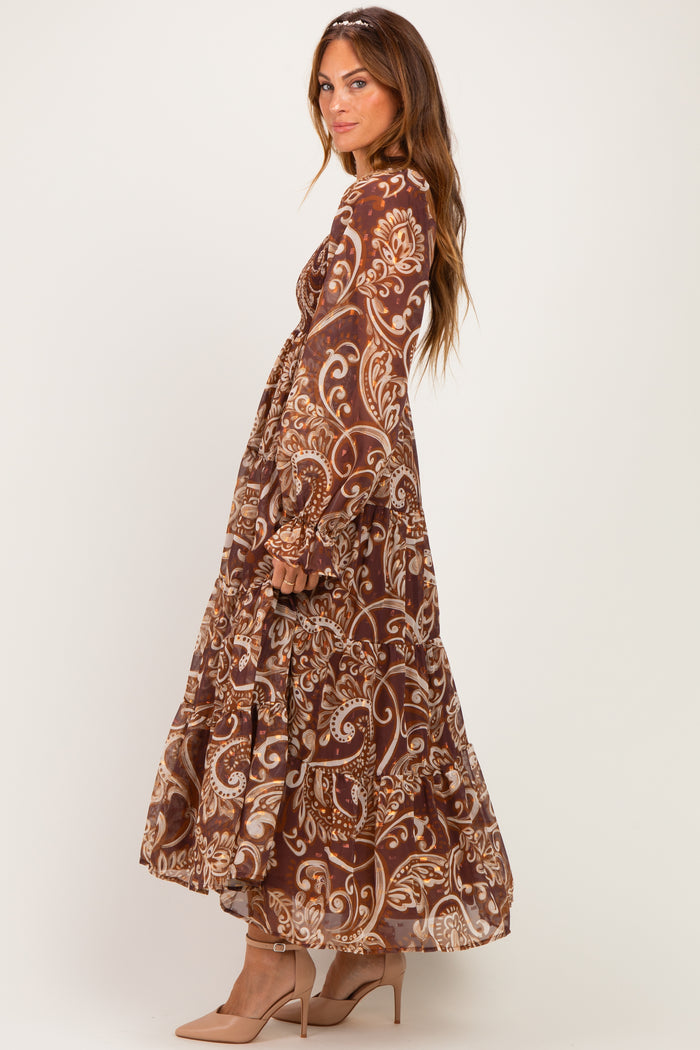woman wearing a long brown bohemian maxi dress with paisley print and puff sleeves, paired with nude heels