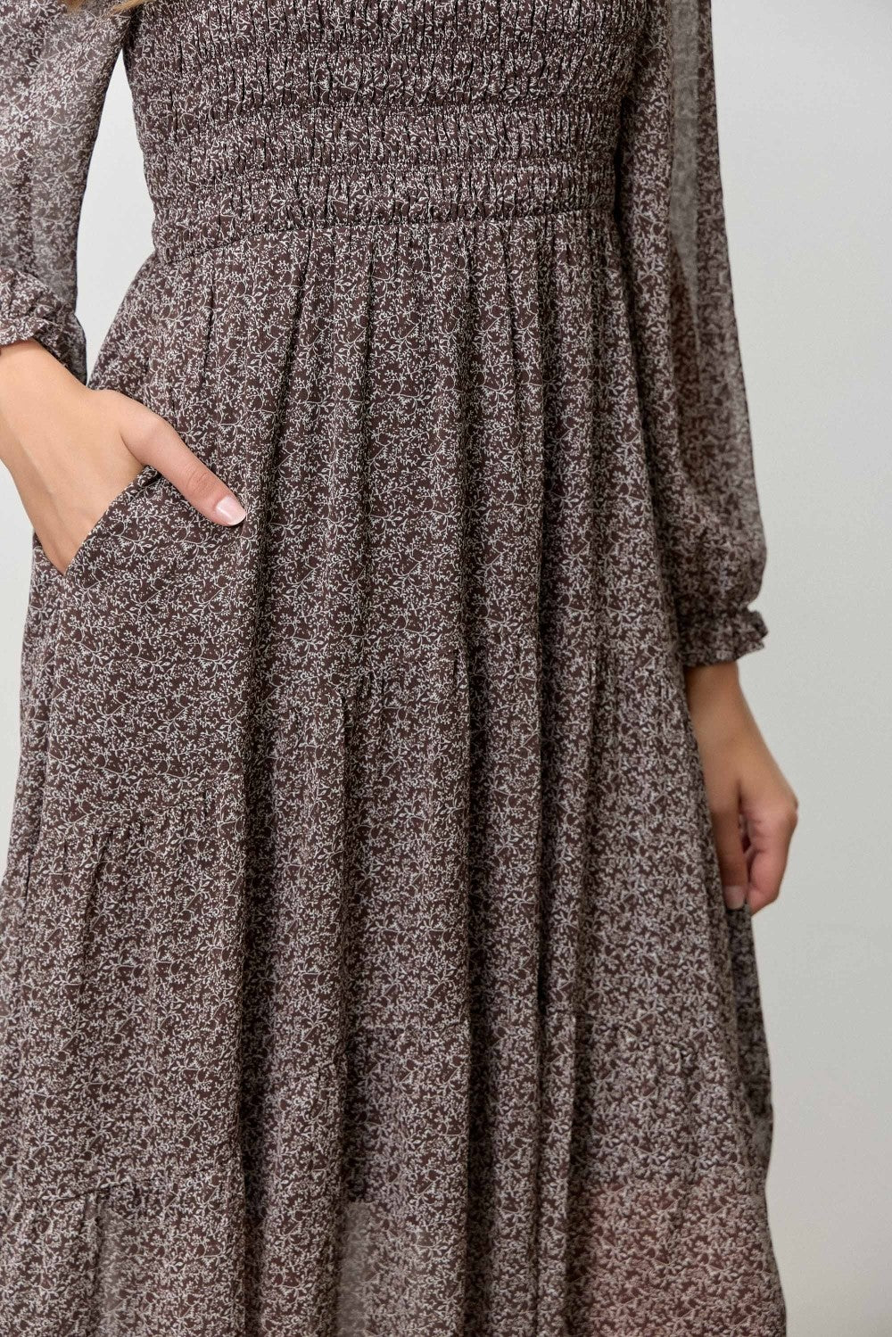 woman wearing a brown floral smocked maxi dress with long sleeves and pockets