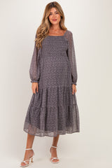 woman wearing a floral print maternity maxi dress with long sleeves and a tiered skirt, showing her baby bump