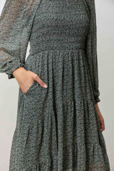 woman wearing a green floral smocked maxi dress with long sleeves and pockets