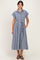 woman wearing a navy blue gingham midi dress with short sleeves and a tie belt, standing with hands in pockets