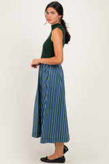 woman wearing a green sleeveless top and a blue and green striped midi skirt