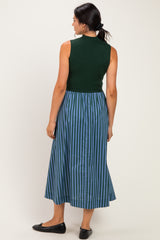 woman wearing a dark green sleeveless top and a blue and green striped midi skirt, viewed from the back