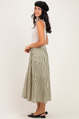 woman wearing a white tank top and a green and white striped midi skirt, styled with a black beret and flats