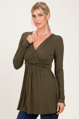 woman wearing an olive green long sleeve wrap top with a twisted detail at the waist and a flattering A-line silhouette