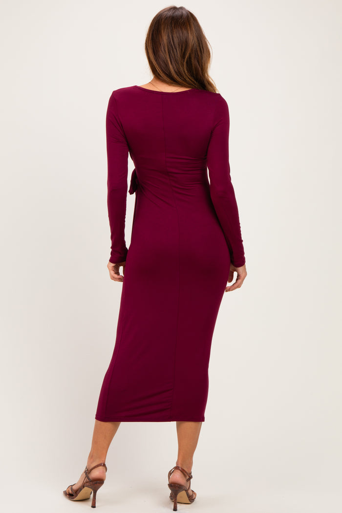 woman wearing a burgundy long sleeve midi dress with a fitted silhouette and tie detail at the waist