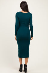 woman wearing a fitted teal long sleeve midi dress, viewed from the back, paired with black ankle boots