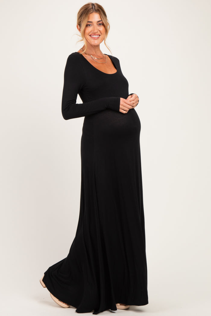 woman wearing a black long sleeve maternity maxi dress and cradling her baby bump