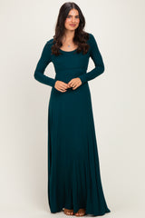 woman wearing a teal long sleeve maxi dress with a fitted bodice and flowy skirt