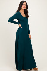 woman wearing a long sleeve teal maxi dress with a fitted bodice and flowy skirt