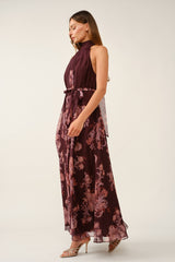 woman wearing a burgundy floral maxi dress with a high neck and tie waist detailing