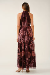 woman wearing a burgundy floral halter neck dress with a flowing skirt, shown from the back