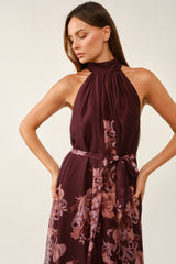 woman wearing a burgundy floral halter neck dress with a waist tie detail