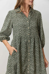 woman wearing a green floral print button-up dress with three-quarter sleeves and pockets
