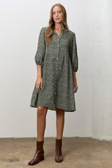 woman wearing an olive green floral button-up dress with puff sleeves and brown ankle boots