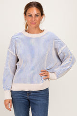 woman wearing a striped light blue and beige oversized sweater with balloon sleeves and casual blue jeans