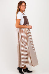 woman wearing a brown and white striped maxi dress with a fitted bodice and flowing skirt, paired with black ankle boots